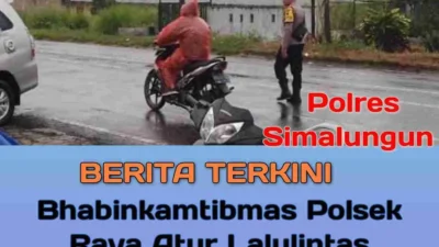 Dalam Deras Guyuran Hujan Bhabinkamtibmas Polsek Raya tetap Bertugas Atur Lalulintas 